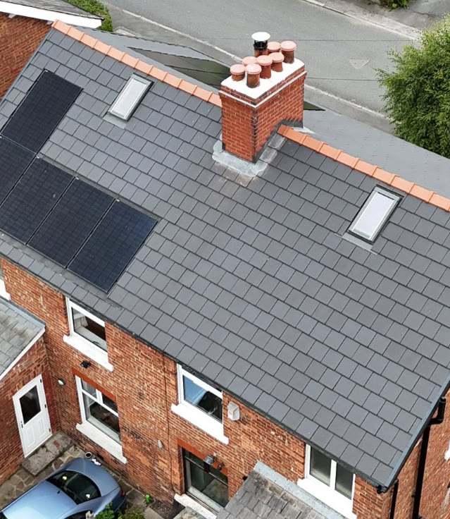 Dark tiled roof with terracotta ridge, brick chimney pots and two skylights