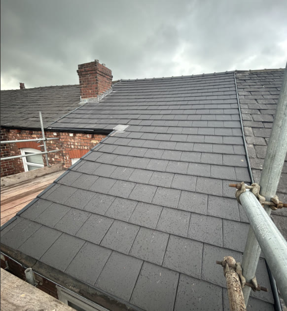 New charcoal tiles on a brick gable, photographed from scaffolding